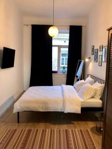 a bedroom with a bed with white sheets and a window at Park apartment in the heart of the city in Lviv