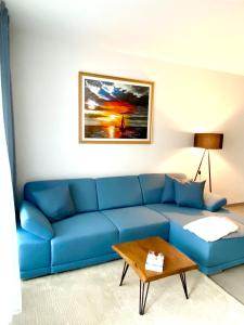 ein blaues Sofa im Wohnzimmer mit einem Tisch in der Unterkunft Fewo unweit Warnemünde Sobierajczyk in Markgrafenheide in Rostock