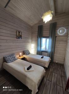 two beds in a room with wooden walls and wooden floors at Travel inn Villas in Velikiy Novgorod