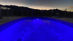 a blue swimming pool with a sunset in the background at Cabañas NAOL in Uspallata
