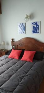 ein Bett mit zwei roten Kissen in einem Schlafzimmer in der Unterkunft De Las Artes XII - triplex sólo familias in Pinamar
