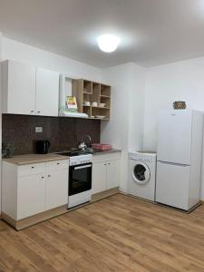 une cuisine avec des armoires blanches et une laveuse et une sécheuse dans l'établissement Rowing Base Apartment, à Plovdiv