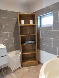 baño con estante de madera junto a un lavabo en logement atypique, en Arles