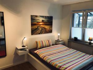 um quarto com uma cama com um quadro na parede em Bungalow am Stadtwald, 24h Check-in em Wolfsburg