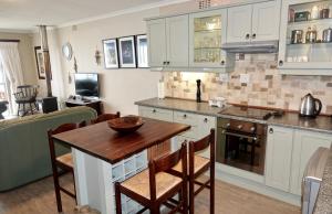 a kitchen with white cabinets and a wooden table at House 10-on-Sea in Hermanus