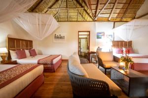 a hotel room with two beds and a table and chairs at Crater Safari Lodge in Kibale Forest National Park