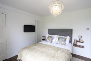 1 dormitorio con cama y lámpara de araña en Northumberland-Hideaways en Kielder