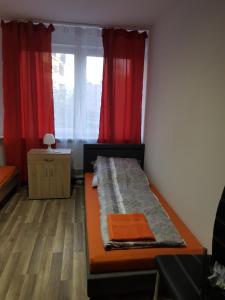 Zimmer mit einem Bett mit roten Vorhängen und einem Fenster in der Unterkunft Duisburg Beeck in Duisburg