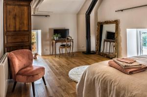 a bedroom with a bed and a chair and a mirror at Au fil de l'eau in Le Vast