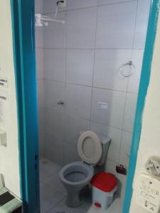 a bathroom with a toilet and a red trash can at Dormitorios Rosario in Pirenópolis