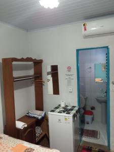 a small kitchen with a refrigerator and a sink at Dormitorios Rosario in Pirenópolis