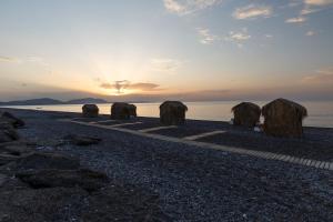 a group of hay huts on the beach at sunset at Eco Beach And Magic Garden Hotel in Gennadi