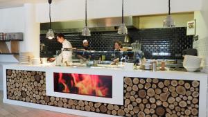 a kitchen with a counter with people preparing food at The Originals Access, Hôtel Millau Sud in LʼHospitalet-du-Larzac