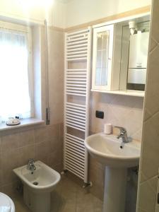 a bathroom with a sink and a toilet and a mirror at Appartamento Castellaccio in Ponte di Legno