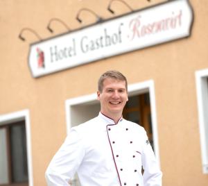 um homem com um uniforme de chefs em frente a um edifício em Hotel Gasthof Rosenwirt em Au in der Hallertau