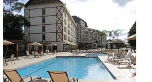 a large swimming pool with chairs and a building at Cond Vista Azul in Pedra Azul