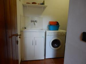 a laundry room with a sink and a washing machine at Oliveto Cottage in Capannori
