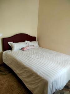 Una cama con sábanas blancas y una muñeca rosa. en Amber Apartments G2 Kitengela en Athi River
