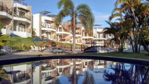a swimming pool with palm trees and a building at Brisas do Amor 131 in Pipa