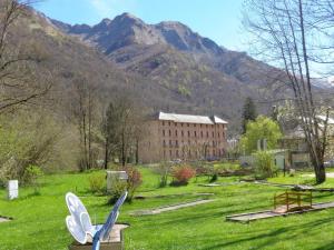 a building in a field with mountains in the background at T2 + Tout Confort + Terrasse in Aulus-les-Bains