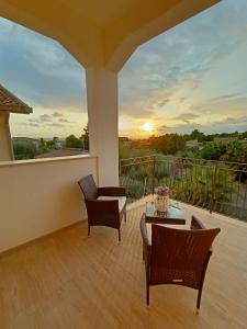 B&B Villa Sara Falconara في ليكاتا: شرفة مع طاولة وكراسي وغروب الشمس