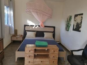 een slaapkamer met een bed en een houten tafel bij la maison du nord in Acoua