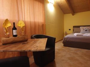 Cette chambre comprend un lit et une table avec une bouteille de vin. dans l'établissement Chalet Chapeau b&b, à Castel Condino