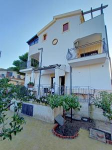 a white house with a balcony and some trees at B&B Villa Sara Falconara in Licata