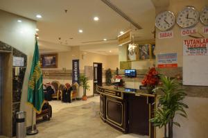 a lobby with a counter and clocks on the wall at Al Bostan Al Masi Hotel in Mecca