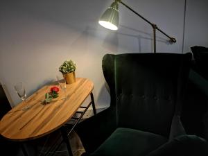 a wooden table with a flower and glasses and a chair at Apartamenty LENA 5 Jacuzzi in Racibórz