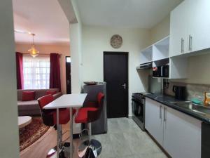 a kitchen with a table and red chairs in a room at Elegant 1 Bedroom Condo Near Vipingo Ridge Golf Resort in Kilifi
