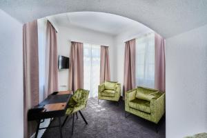 a hotel room with a desk and chairs and windows at Hotel Zur Post Altötting in Altötting