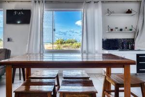 a large wooden table in a kitchen with a large window at Mykonos Residence in São Miguel do Gostoso