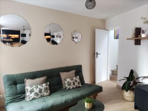 a living room with a green couch and two mirrors at My Duplex House Trouville in Trouville-sur-Mer