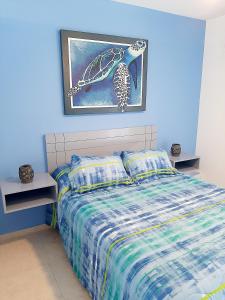 ein blaues Schlafzimmer mit einem Bett und einem Bild an der Wand in der Unterkunft Ocean Villa in Puerto Morelos