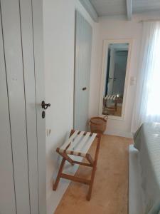 a bedroom with a wooden chair and a mirror at Simos suites in Elafonisos
