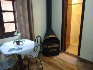 a room with a stove and a table and a fireplace at Chale Aroma da Serra in Monte Verde