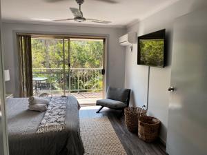 een slaapkamer met een bed, een stoel en een raam bij Superb Villa in Beach Resort in Coffs Harbour