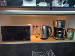 a microwave and a coffee maker on a shelf at Appartement T2 "JUNGLE" Centre Ville de VITRÉ au calme coté cour in Vitré