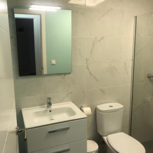 ein Badezimmer mit einem WC, einem Waschbecken und einem Spiegel in der Unterkunft Alojamiento Torrevieja playa frente al mar in Torrevieja