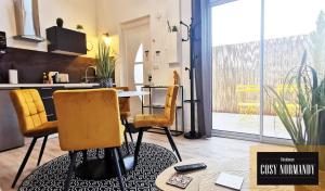 ein Wohnzimmer mit einem Tisch und Stühlen sowie eine Küche in der Unterkunft Cosy Normandy - 02 in Bois-Jérôme-Saint-Ouen