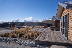 a house with a wooden deck with mountains in the background at Number 8 - Lake Tekapo in Lake Tekapo