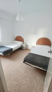 2 Betten in einem Zimmer mit weißen Wänden in der Unterkunft Precioso apartamento en la playa de Bellreguard in Bellreguart