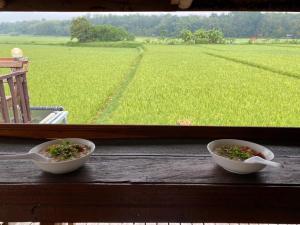 dos tazones de comida sentados en una ventana mirando un campo en Nan View Farmmer Lumduan Homestay, en Nan