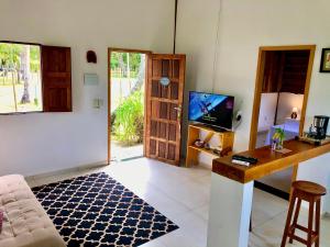 Das Wohnzimmer ist mit einem TV, einem Tisch und einem TV ausgestattet. in der Unterkunft Chalezinho Super Equipado em Caravelas in Caravelas