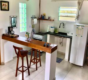 eine Küche mit einem Tisch und einem Kühlschrank in der Unterkunft Chalezinho Super Equipado em Caravelas in Caravelas