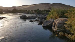 a river with rocks and a mountain in the background at Adad Noubian House in Aswan