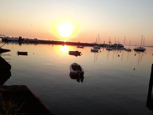 a boat in the water with the sunset in the background at Posada Mela in Colonia del Sacramento