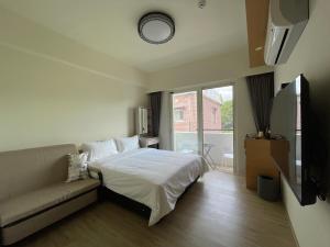 a bedroom with a bed and a couch and a window at 墾丁星院旅宿 in Kenting