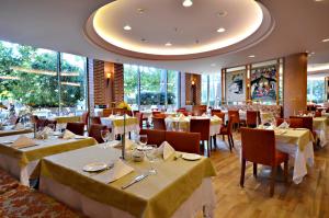 a restaurant with white tables and chairs and windows at Gloria Verde Resort - Kids Concept in Belek